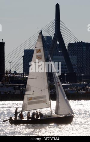 Un voilier traverse le port de Boston avec le pont commémoratif Leonard P. Zakim Bunker Hill derrière lui à Boston, Massachusetts. Banque D'Images