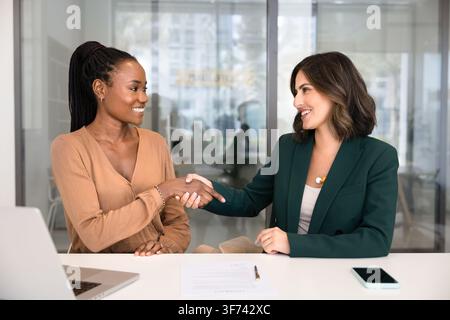 Deux femmes d'affaires multiethniques se serrant la main au bureau Banque D'Images