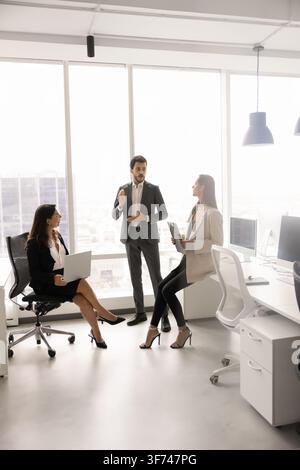 Trois professionnels discutant du travail dans un bureau moderne Banque D'Images