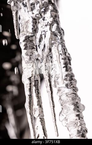 Crampons acérés suspendus à une structure avec des gouttelettes gelées et des éléments d'arrière-plan flous créant une atmosphère hivernale froide, une vue rapprochée détaillée Banque D'Images