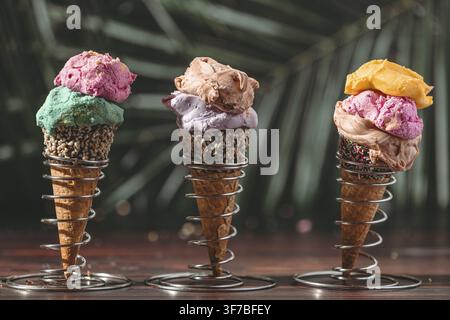 Trois cônes de glace avec une glace colorée sur un fond tropical Banque D'Images