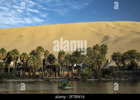 L'oasis de Laguna Huacachina avec un petit lac et des palmiers entourés de dunes de sable dans la région d'Ica, désert côtier, sud du Pérou, Pérou, Amérique du Sud Banque D'Images