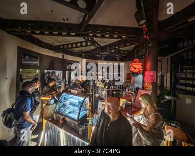 BELGRADE, SERBIE - 6 JUIN 2026 : Intérieur d'un bar animé la nuit à Belgrade, avec des clients rassemblés autour du comptoir, des vitrines éclairées, des boissons, le personnel a Banque D'Images
