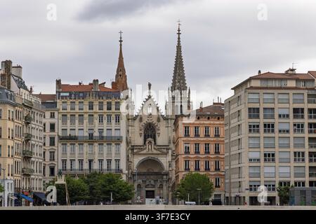 Lyon, France - 27 juillet 2026 : Flèches gothiques et façade de l'église Saint-Nizier entourées de bâtiments historiques sous un ciel nuageux. Banque D'Images