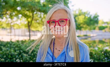Sénior souriant avec des lunettes rouges dans le parc Banque D'Images
