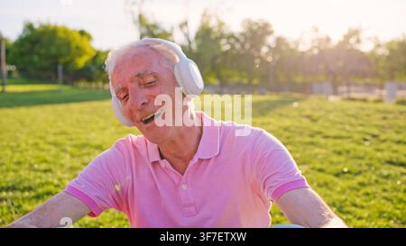 Senior profitant de la musique en plein air avec un casque sans fil Banque D'Images