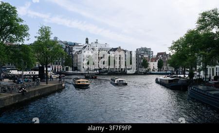 Vue panoramique sur un canal avec une architecture néerlandaise traditionnelle et des bateaux dans le centre historique d'Amsterdam, Pays-Bas Banque D'Images