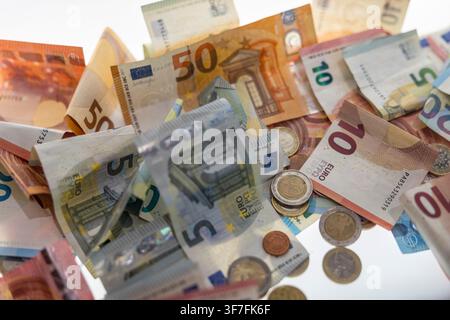 Une nature morte de billets et pièces en euros flottants sur un fond clair, symbolisant la finance, la monnaie et l'économie. Banque D'Images