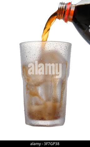 Photo d'action puissante montrant un liquide Coca-Cola sortant d'une bouteille dans un verre rempli de glace, capturé à mi-versement sur fond blanc propre. Phot énergie de marque Banque D'Images