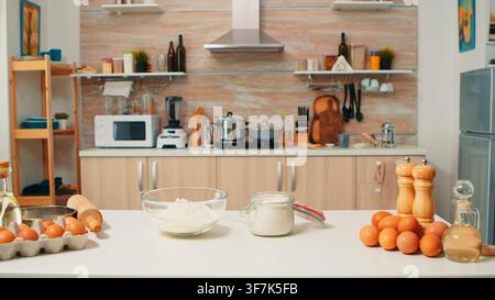 La zone de repas et de cuisine moderne est aménagée avec des ingrédients bruts pour la préparation de pain et de gâteaux, à une table préparée pour la pâtisserie maison pendant la mise en place des ingrédients. Banque D'Images