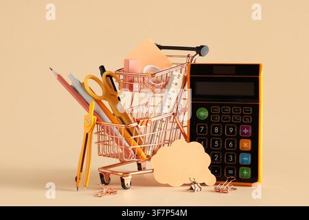 Panier miniature rempli de fournitures scolaires et d'une calculatrice sur un fond beige, retour à l'école Banque D'Images