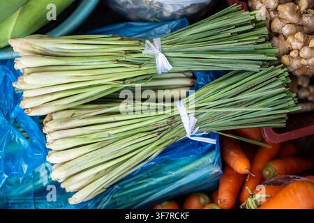 Botte de tiges de citronnelle vertes liées avec du fil au comptoir d'une boutique vendant en plein air sur un marché de rue. Banque D'Images