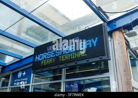 Horseshoe Bay, Canada – 27 juillet 2026 : Un panneau LED numérique indique « Bienvenue au terminal de ferry de Horseshoe Bay » sous le dais en acier bleu et en verre du Banque D'Images