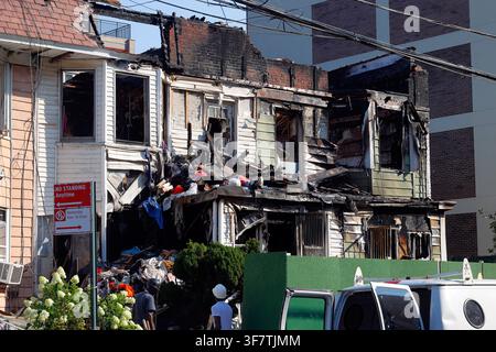 Des ouvriers arrivent pour nettoyer après un incendie survenu à plusieurs maisons à charpente en bois au 41st Rd à Flushing, Queens County, New York, le 25 juillet 2026. Banque D'Images