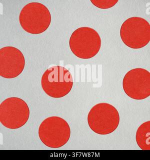 Des points rouges circulaires créant un motif géométrique sur du papier texturé gris. Effet grunge, bruit et flou de mouvement appliqués Banque D'Images