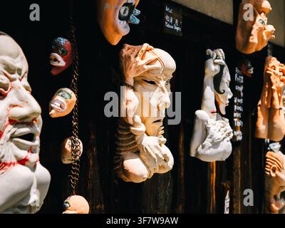 Masks traditionnels japonais Noh et démon affichés sur un mur en bois sombre à Kyoto, Japon Banque D'Images