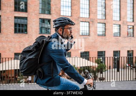 Citadin se rendant à vélo au bureau, portant un sac à dos et un casque. Banque D'Images