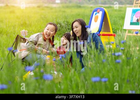 Famille asiatique heureuse avec mère et deux filles prenant un selfie tout en peignant dans un champ de prairie. Banque D'Images