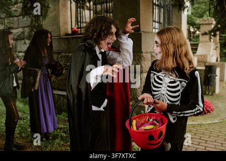 Enfants en costumes d'Halloween jouant et faisant du porte-à-porte à l'extérieur Banque D'Images