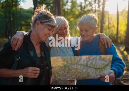 Amies féminines matures explorant la nature avec carte sur le voyage de randonnée. Banque D'Images