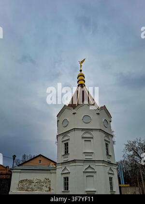 Le clocher du couvent de la Sainte-Trinité se dresse fièrement à Zadonsk. Une figure d'ange doré trône au sommet d'une flèche dorée. Le ciel est nuageux et reflète le Banque D'Images