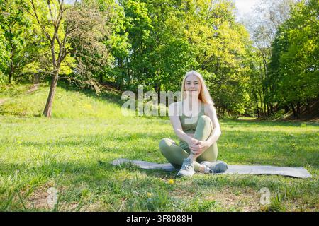 Belle femme blonde d'âge moyen sportive en entraînement en plein air dans un environnement vert Banque D'Images