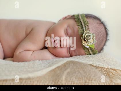 Bébé nouveau-né endormi portant un bandeau fleuri Banque D'Images