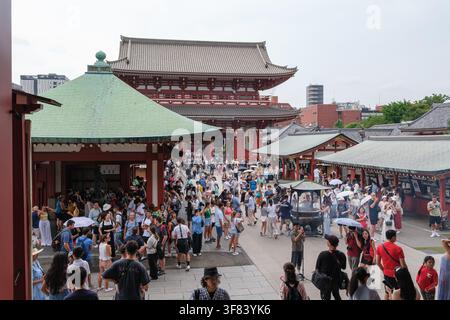 Tokyo, Japon – 7 août 2025 : Zone extérieure animée du temple Senso-ji avec de nombreux visiteurs, une architecture traditionnelle et des toits verts visibles en arrière-plan Banque D'Images