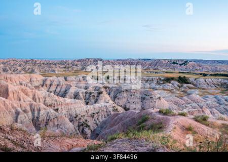 Des falaises érodées mettent en valeur des couches sédimentaires colorées au crépuscule depuis le Big Badlands Overlook dans le parc national des Badlands, Dakota du Sud, États-Unis Banque D'Images