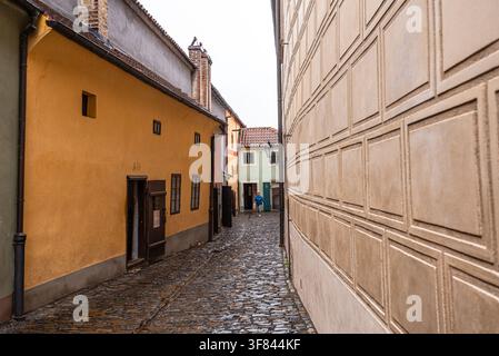 Des maisons colorées bordent le chemin étroit de la Golden Lane au château de Prague, avec des touristes explorant le site historique Banque D'Images