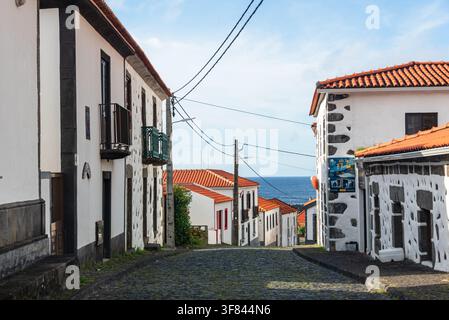 Rue pavée étroite avec des maisons blanches dans un village côtier de l'île de Flores au Portugal Banque D'Images