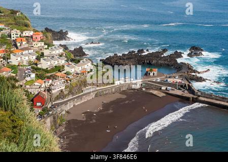 Piscine naturelle et scène de plage à Seixal sur l'île de Madère au Portugal avec une côte rocheuse et des maisons côtières Banque D'Images