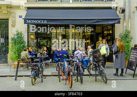 Les gens profitent de boissons et de conversations au café Monocle sur la rue Bachaumont par une journée de printemps à Paris, France Banque D'Images
