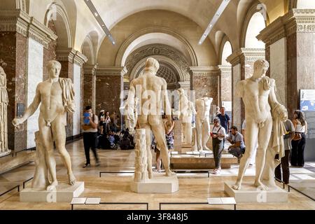 Les visiteurs explorent le musée du Louvre en observant les sculptures dans la salle Banque D'Images