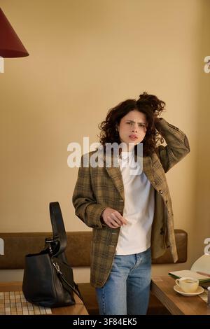 Femme d'affaires aux cheveux bouclés et confuse travaille à distance à une table confortable d'un café Banque D'Images