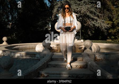 Photographe femme marchant avec son appareil photo dans le parc Banque D'Images