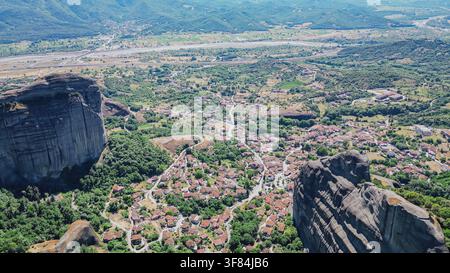 Vue aérienne de dessus du village de Kastraki niché entre d’immenses formations rocheuses dans la vallée de Meteora avec la plaine de la rivière Pinios en arrière-plan en Thessalie, Grèce Banque D'Images
