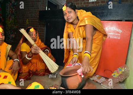 Femme bengali en sari jaune accomplissant le rituel traditionnel hindou Chhath Puja avec un pot en terre cuite et un balai lors d'un festival religieux en Inde. Banque D'Images