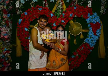 Parents indiens avec un bébé garçon posant devant un fond en forme de cœur avec des roses rouges et bleues et une enseigne Beti dorée lors d'une célébration familiale et d'un événement traditionnel Banque D'Images