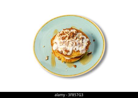 Pile de crêpes avec yaourt crémeux, amandes hachées et sirop de miel dans une assiette bleue Banque D'Images