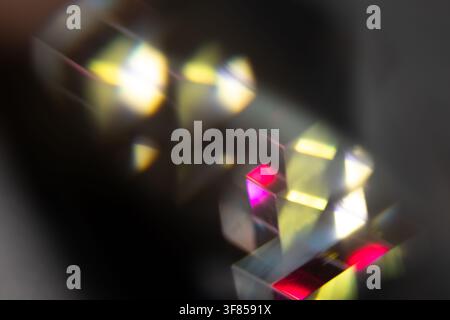 Prismes en verre réfractant une lumière jaune vif, rose et blanche sur un fond sombre pour un design optique abstrait Banque D'Images