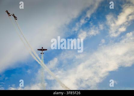 Avion de voltige aérienne effectuant des manœuvres aériennes spectaculaires dans le ciel, libérant de la fumée colorée et des feux d'artifice. Performance aérienne dans le ciel bleu Banque D'Images