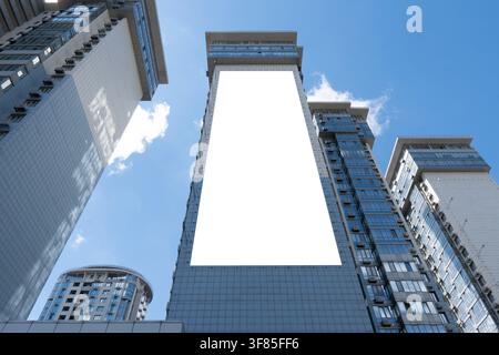 Grand modèle d'affichage vertical blanc vierge sur le mur d'un gratte-ciel moderne. Vue en contre-plongée d'un écran publicitaire extérieur au centre-ville de la métropole Banque D'Images