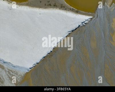 Vue aérienne des textures abstraites de sable blanc et de boue grise le long d'une rive fluviale en Pologne. Banque D'Images