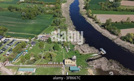 Vue aérienne de la réserve naturelle spéciale de Zasavica présentant la rivière sinueuse, les zones humides luxuriantes, les installations pour les visiteurs et un parking à Zasavic Banque D'Images