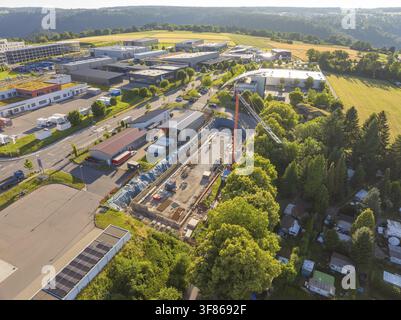 Vue aérienne d'un site industriel avec des activités de construction majeures, adjacent à des champs et des rangées d'arbres, Parkhaus Bau, Calw, Allemagne Banque D'Images