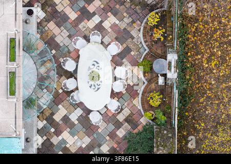 Vue aérienne d'un espace de restauration extérieur comprenant une table ovale blanche avec des chaises posées sur une terrasse en pierre multicolore à Belgrade, en Serbie. Banque D'Images