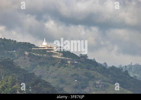Temple majestueux perché sur un paysage montagneux tropical verdoyant sous un ciel nuageux avec un chemin sinueux. Vue depuis le Little Adam's Peak au Sri Lanka Banque D'Images