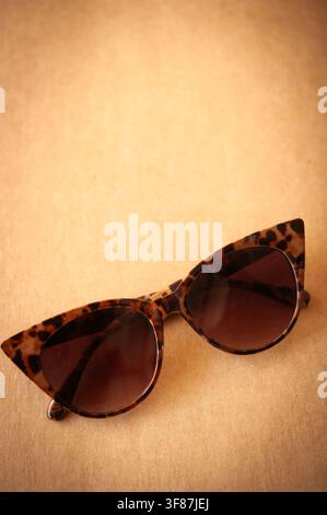 Lunettes de soleil œil de chat écaille de tortue reposant sur une surface brun chaud avec un flou d'arrière-plan doux et un espace de copie généreux Banque D'Images