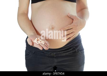 Femme enceinte tenant une pilule, isolée sur fond blanc Banque D'Images